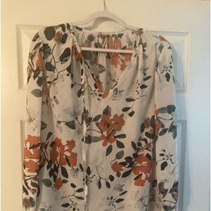 White blouse with dark green leaves and coral flower design.